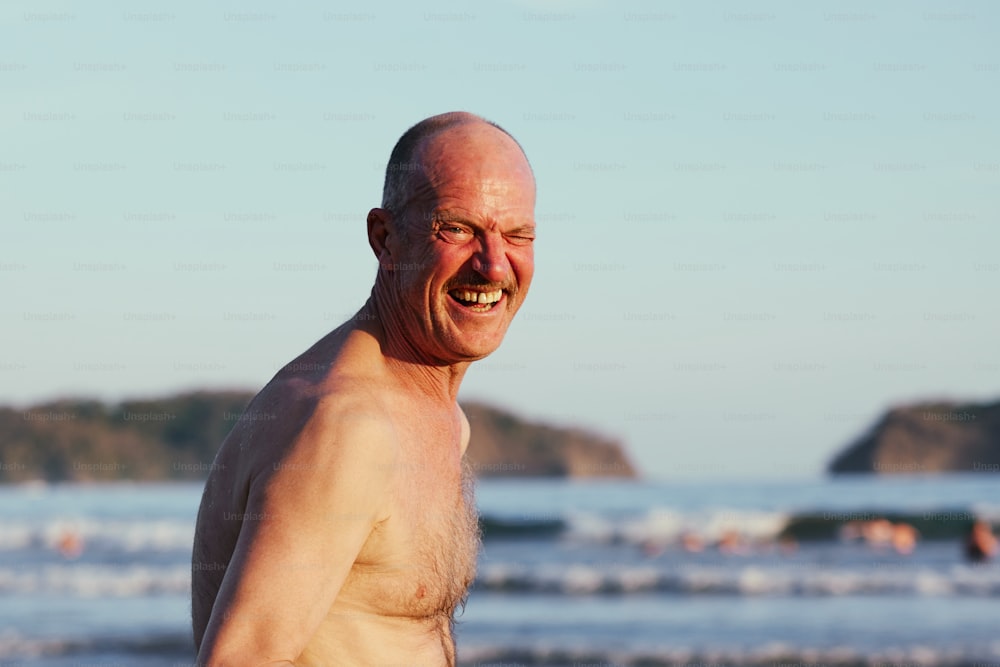 an older man standing on a beach next to the ocean