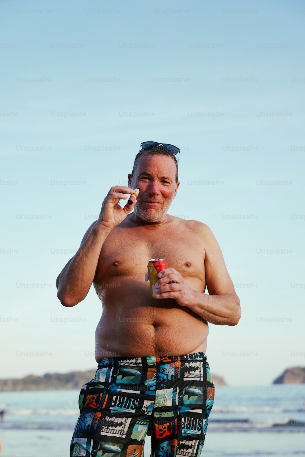 a man standing on the beach talking on a cell phone