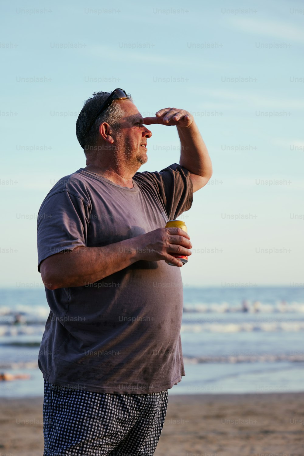 Un uomo in piedi su una spiaggia con in mano un frisbee giallo