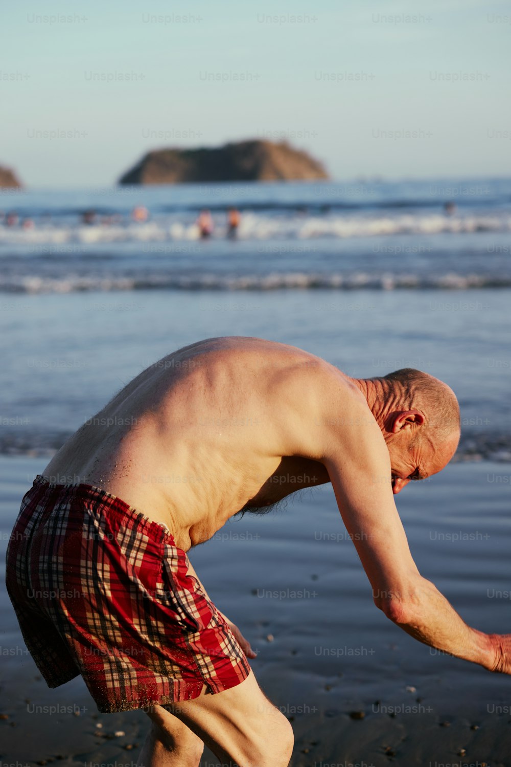 Ein Mann, der sich bückt, um einen Frisbee am Strand aufzuheben