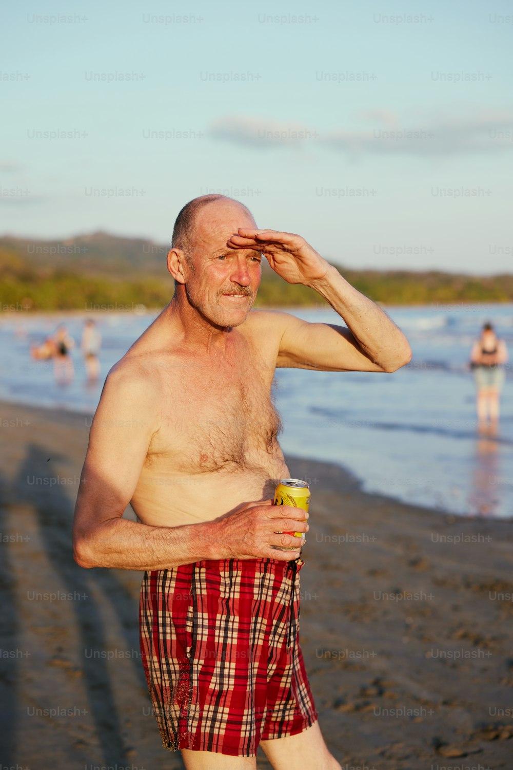 um homem em pé em uma praia segurando uma xícara de café