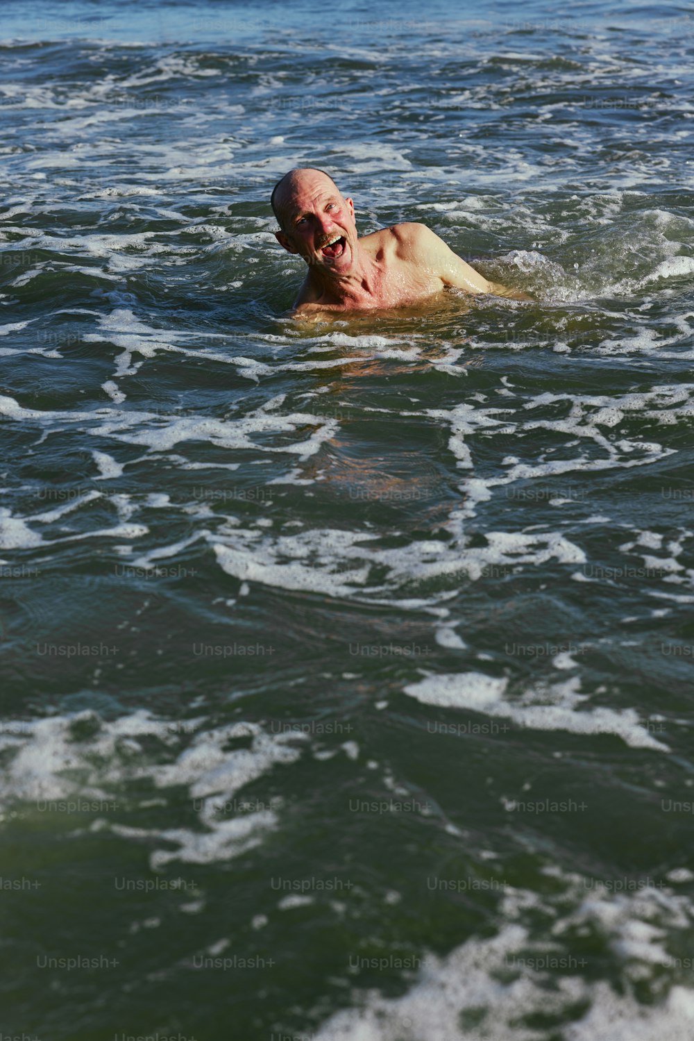 頭を水面上にして海を泳ぐ男