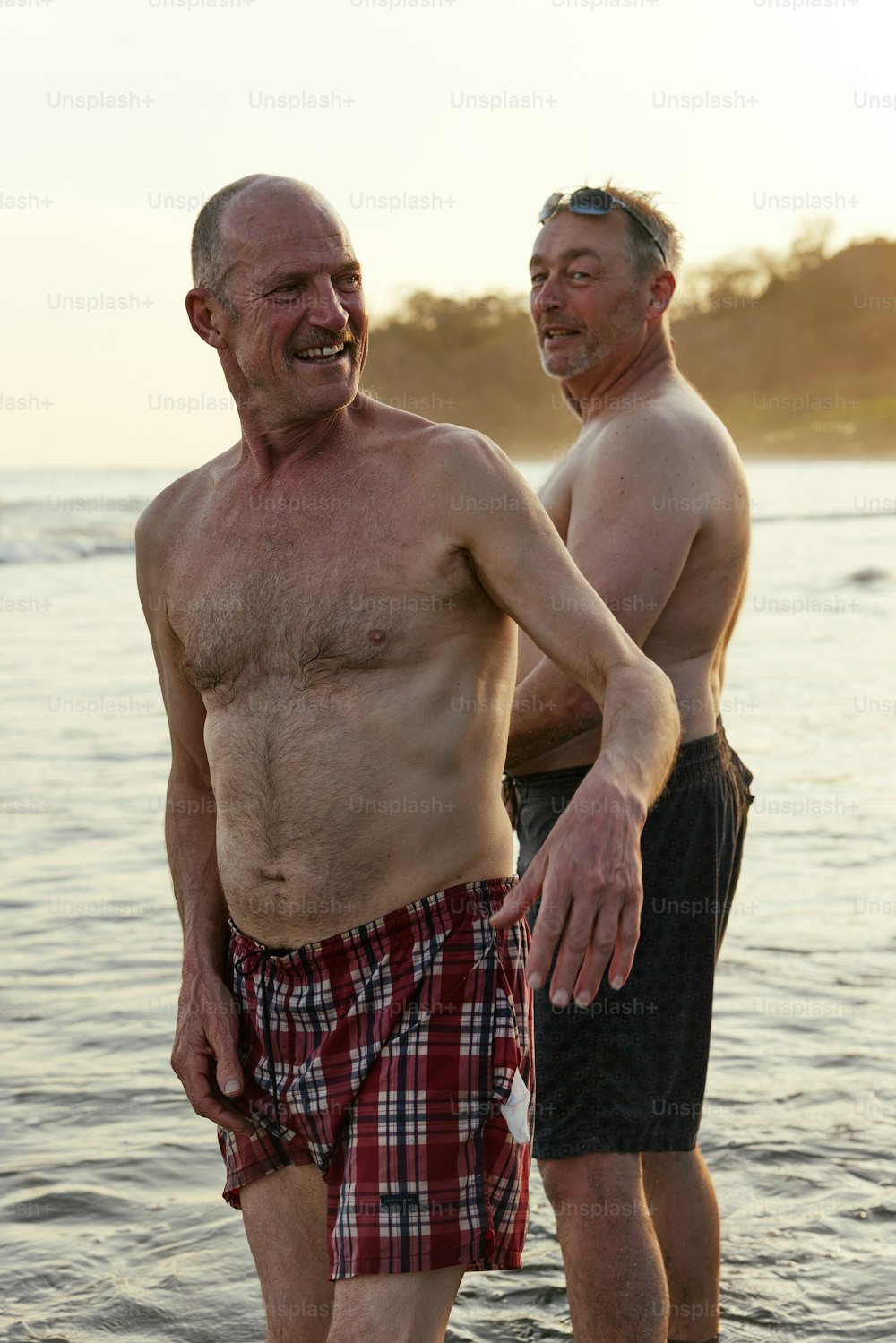 two older men standing in the water at the beach