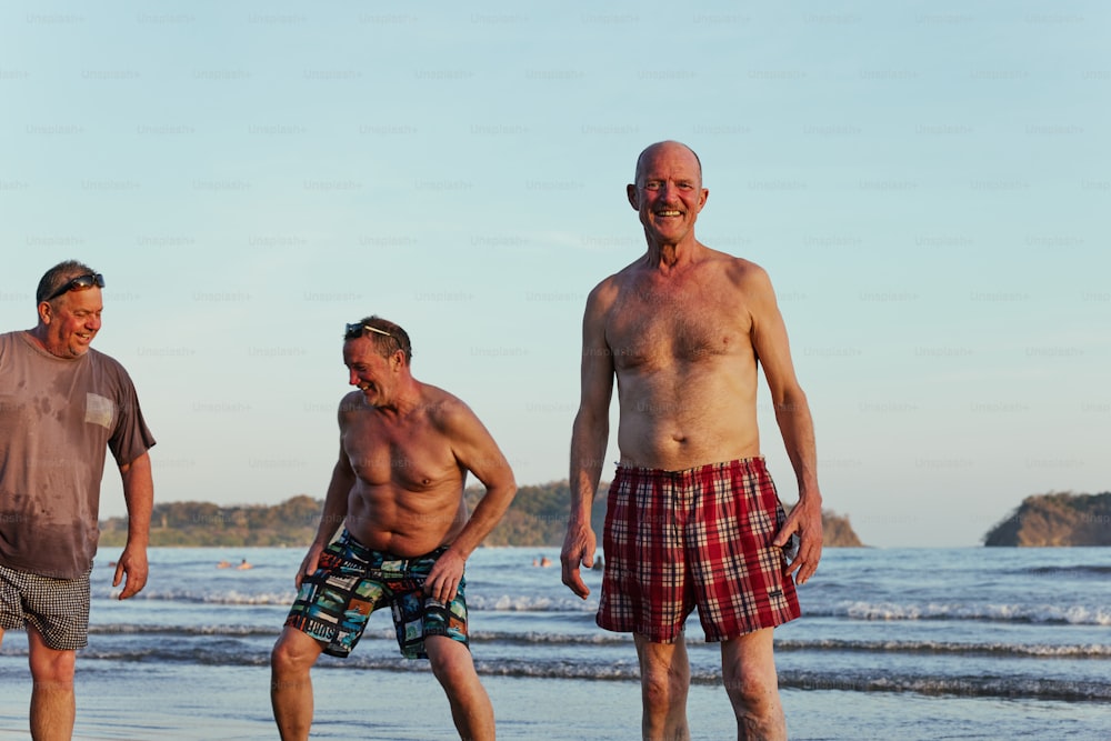 a group of men standing on top of a beach next to the ocean