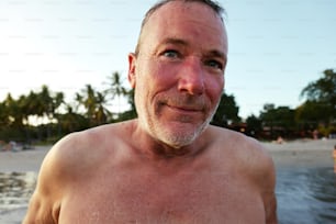 a man with no shirt on standing in front of a body of water