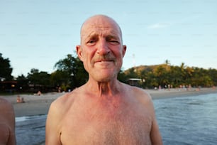 an older man standing on a beach next to the ocean