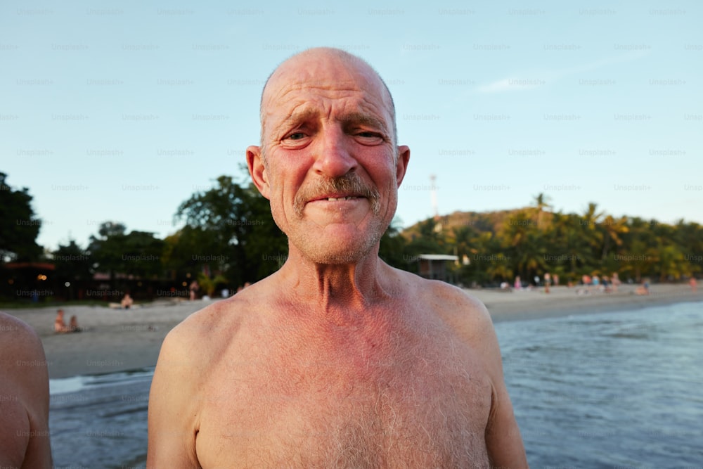 um homem mais velho de pé em uma praia ao lado do oceano