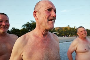 three older men standing next to each other on a beach