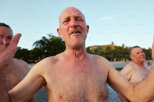 a man without a shirt standing in front of a body of water