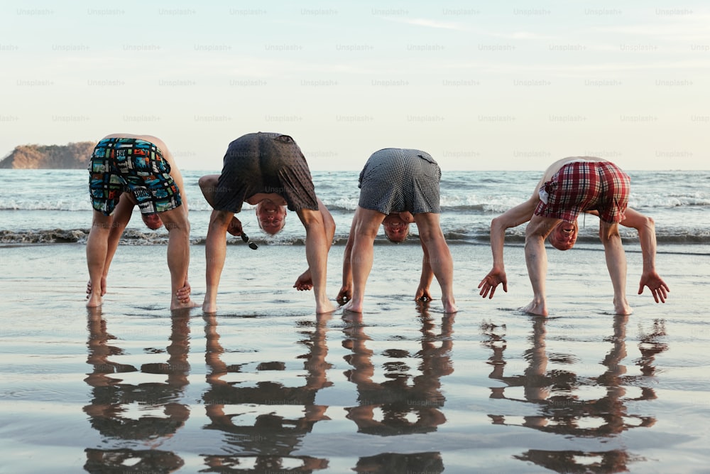 um grupo de pessoas fazendo um handstand na praia