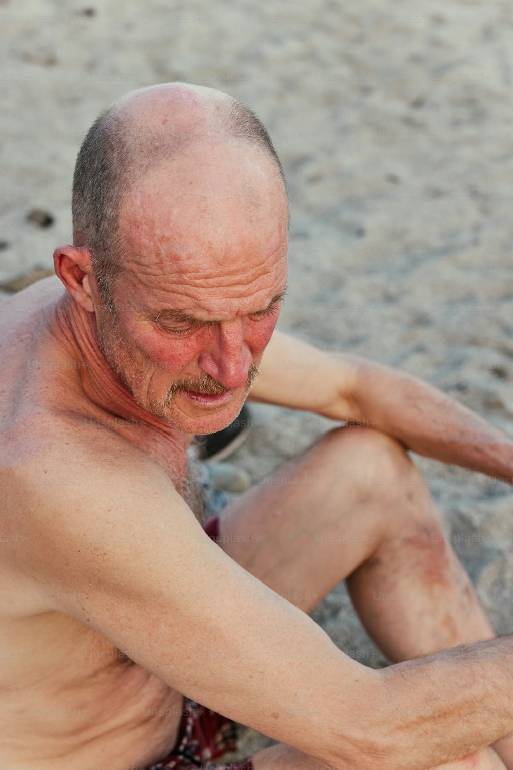 Un hombre sentado en la playa con un frisbee en la mano