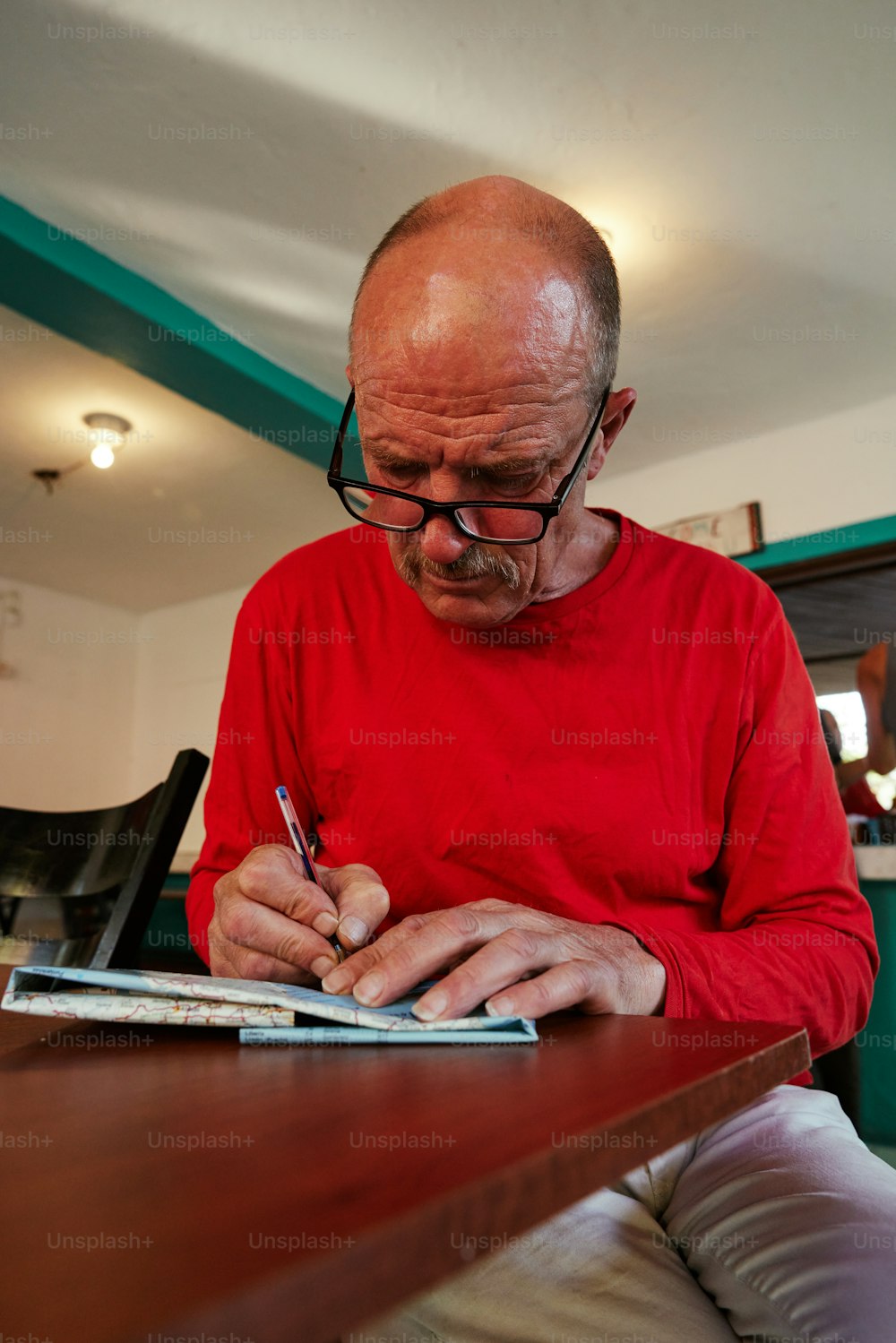 a man in a red shirt writing on a piece of paper