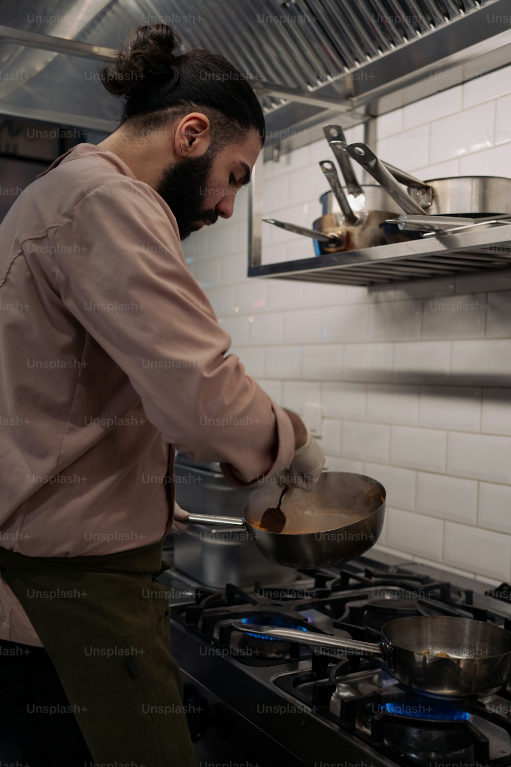 a man cooking on a stove top in a kitchen