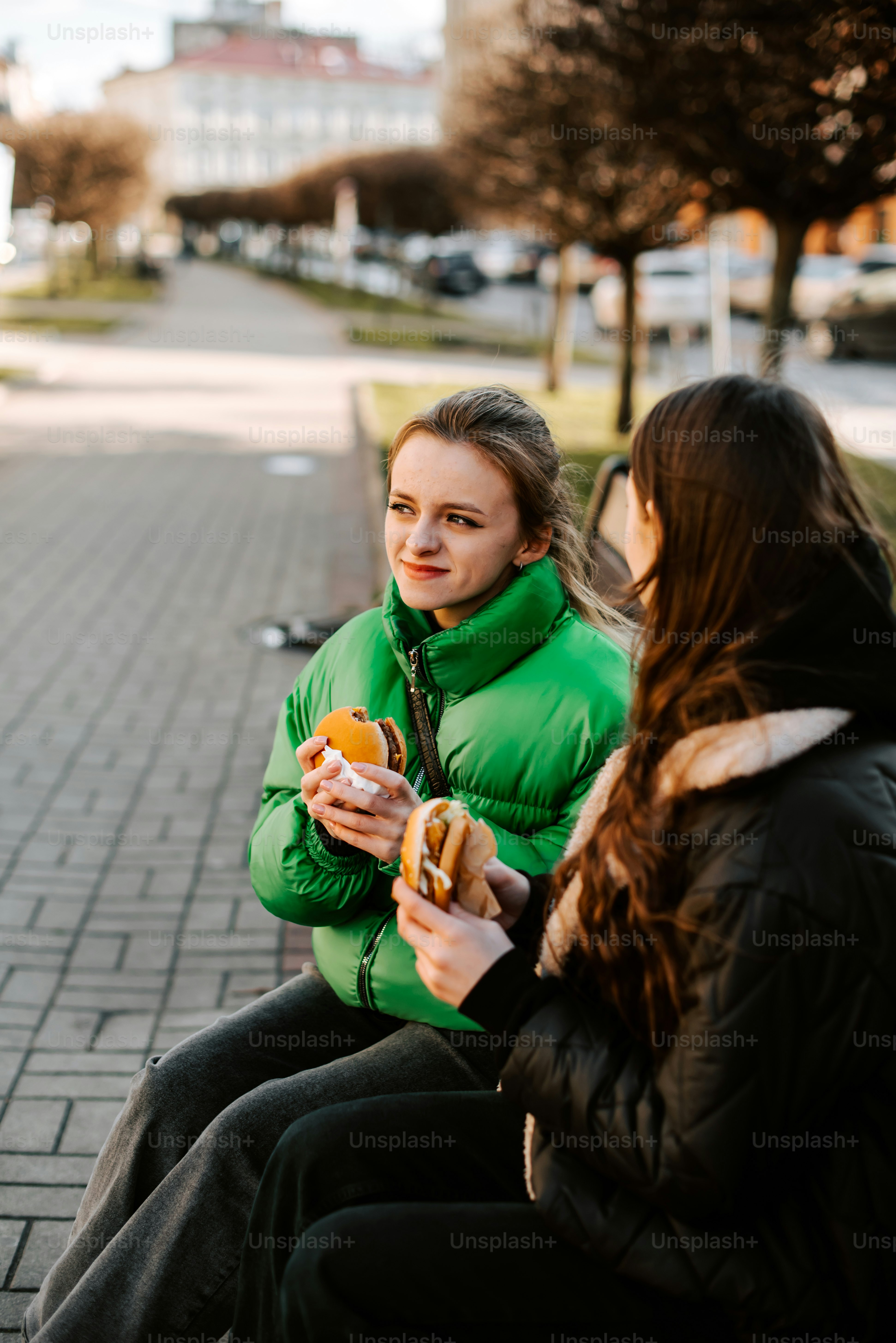 a woman sitting on a bench eating a hot dog