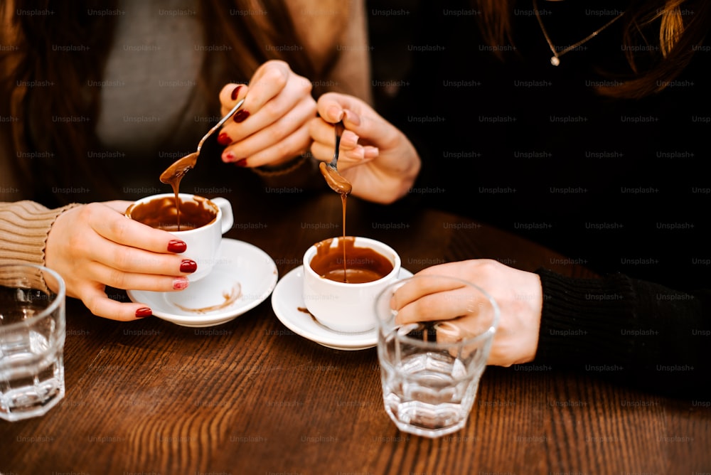 um casal de pessoas sentadas em uma mesa com xícaras de café