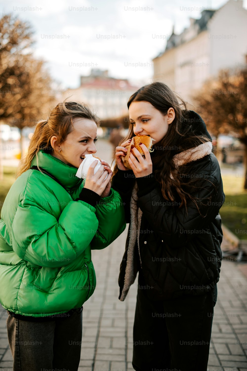 보도에 서서 음식을 먹는 두 여자