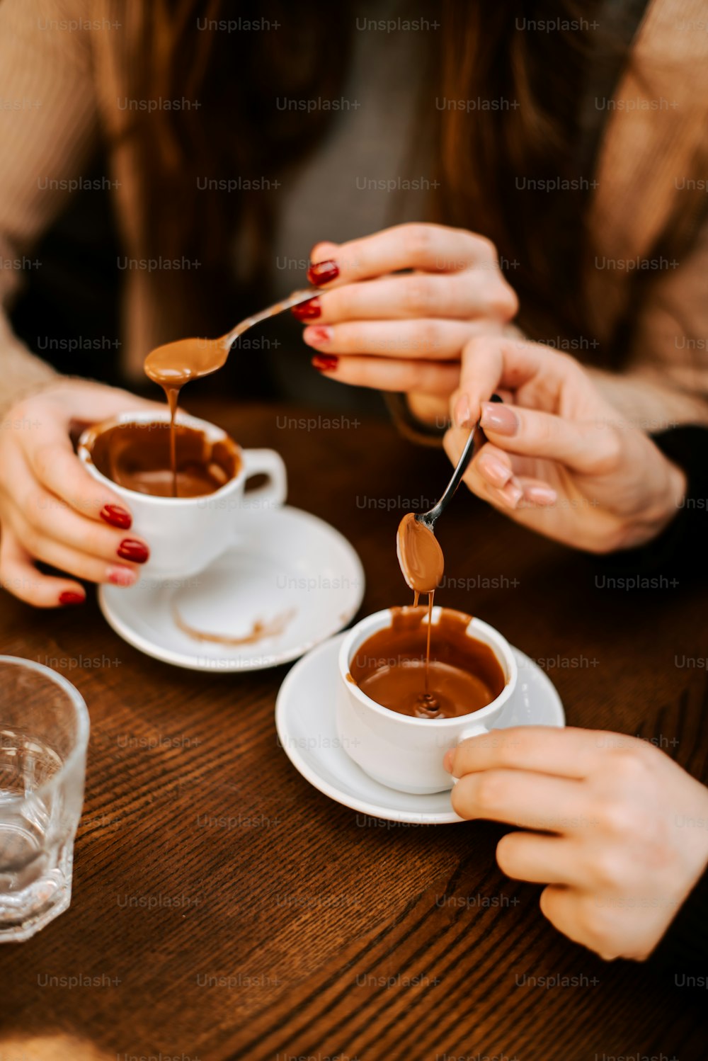 two people sitting at a table with two cups of chocolate