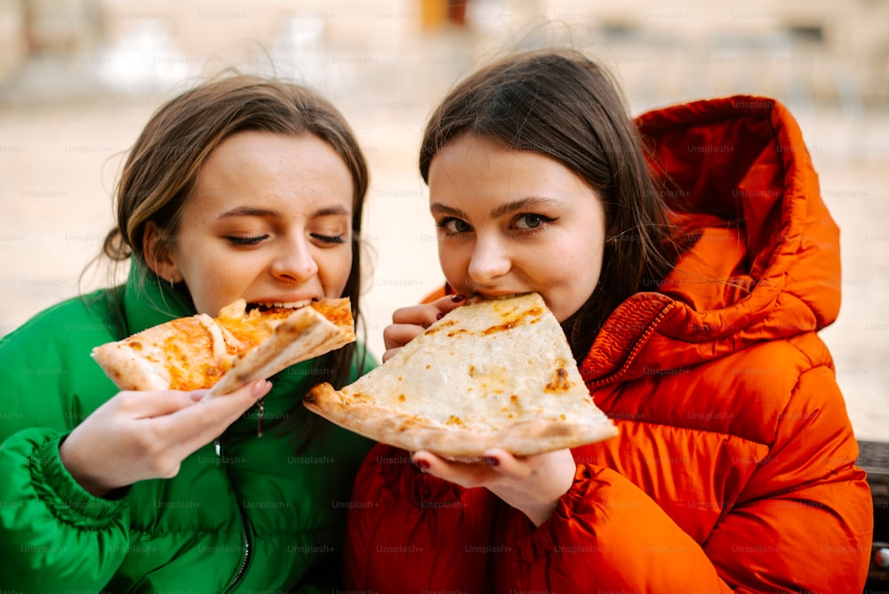 two girls are eating a large piece of pizza