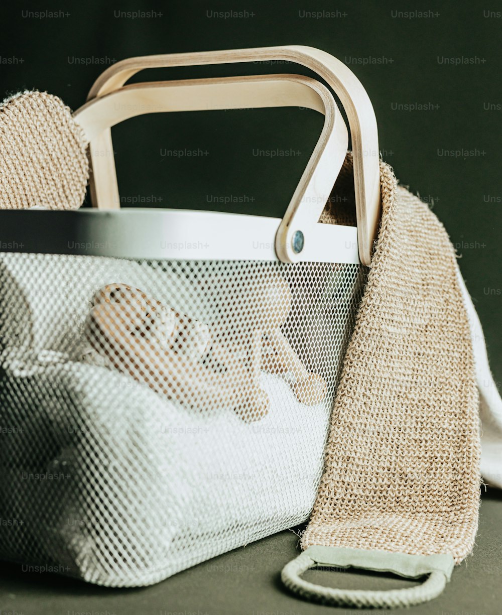 a white basket with a wooden handle next to a white towel