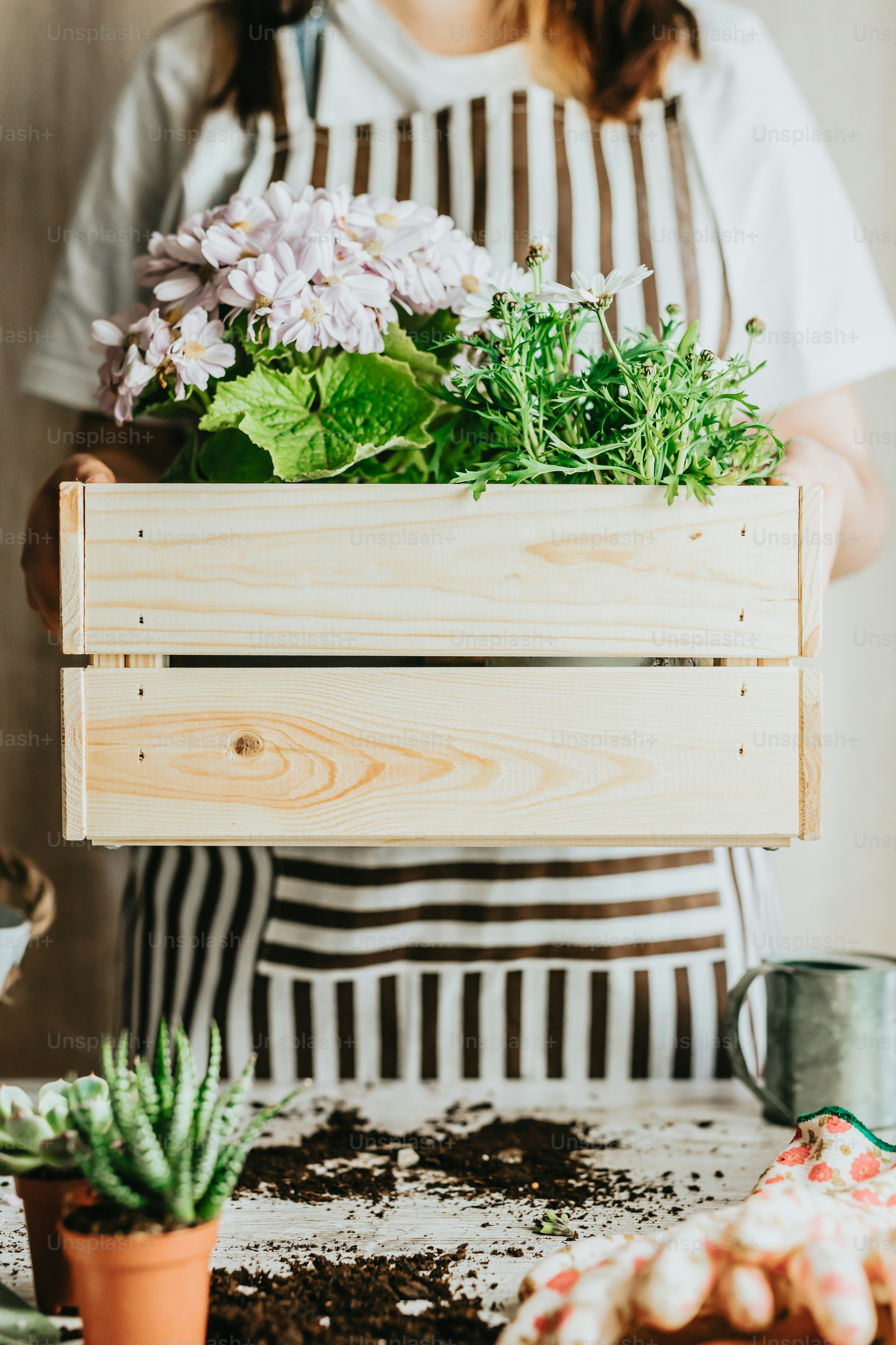a woman holding a wooden crate filled with flowers
