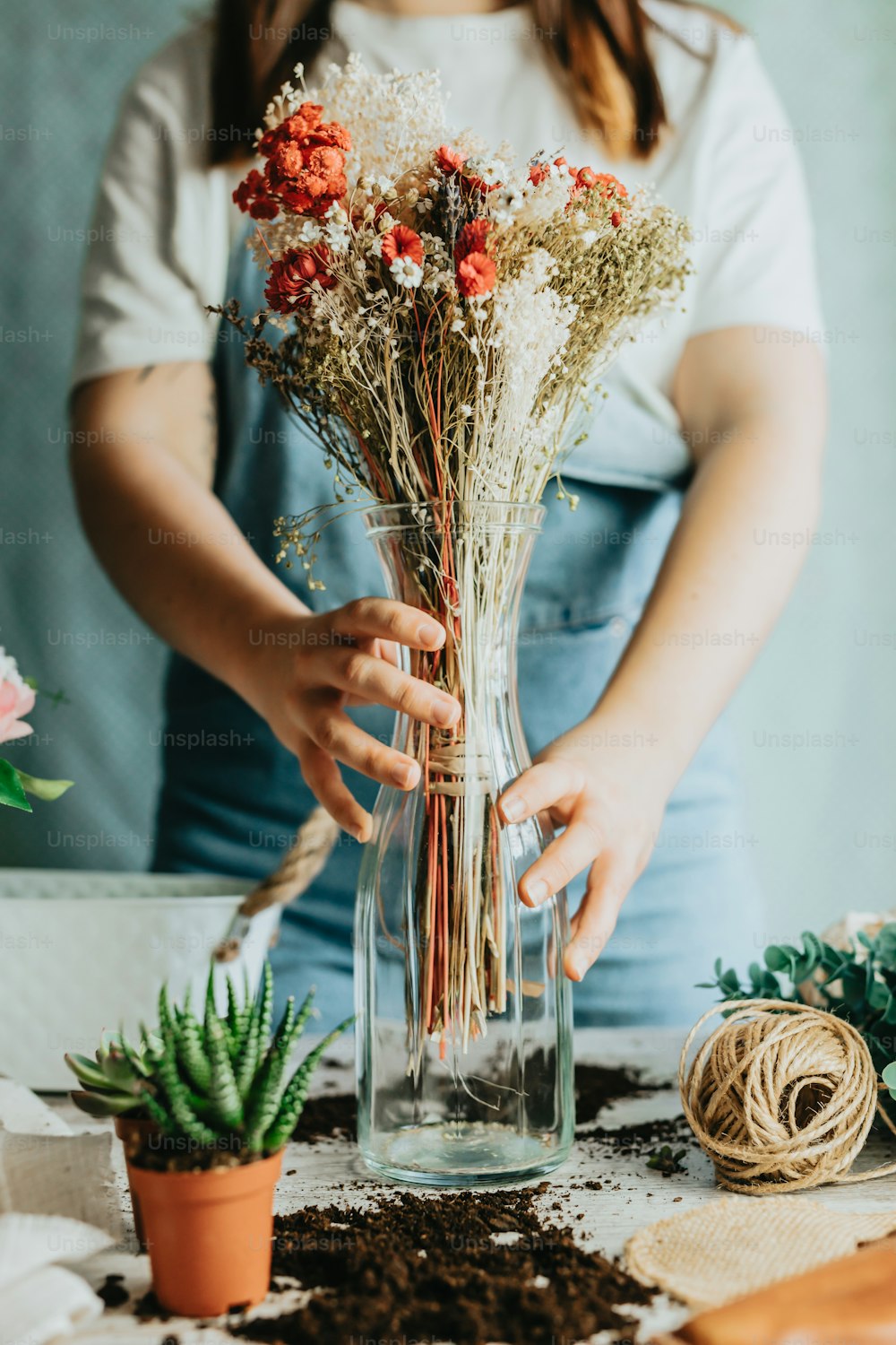 Eine Frau, die Blumen in einer Vase auf einem Tisch arrangiert