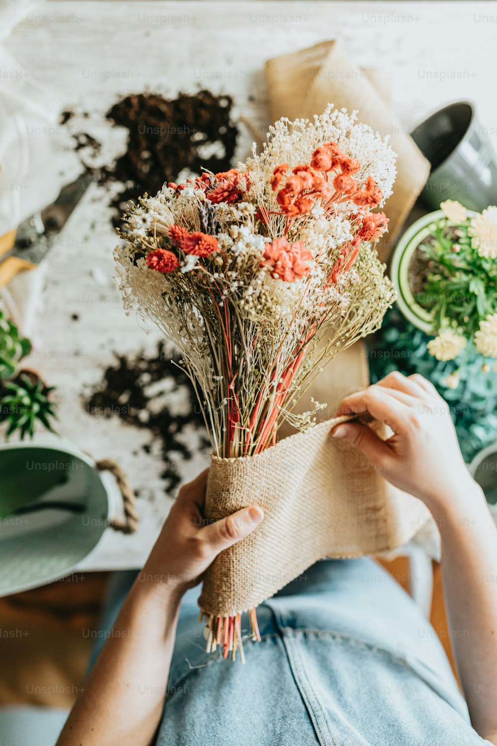 a person holding a bunch of flowers on top of a table