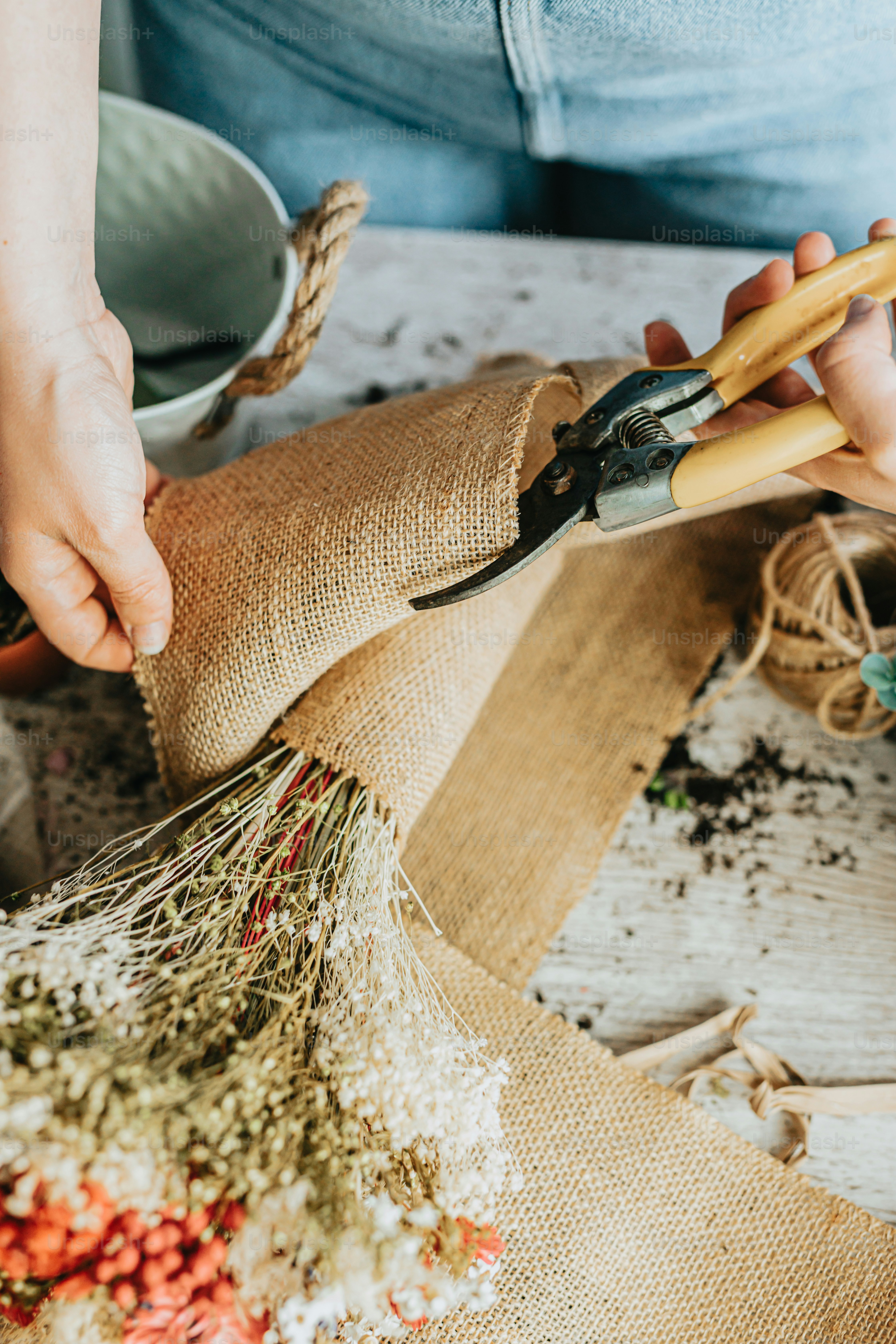 a person using a pair of scissors to cut a piece of burlock