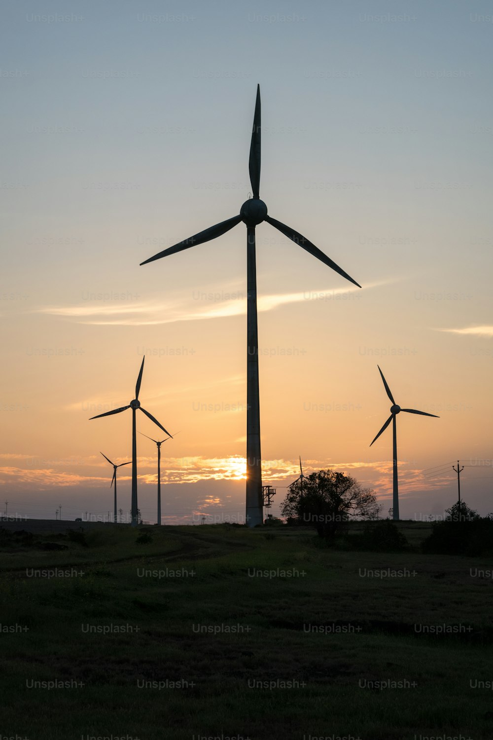 a group of windmills in a field at sunset