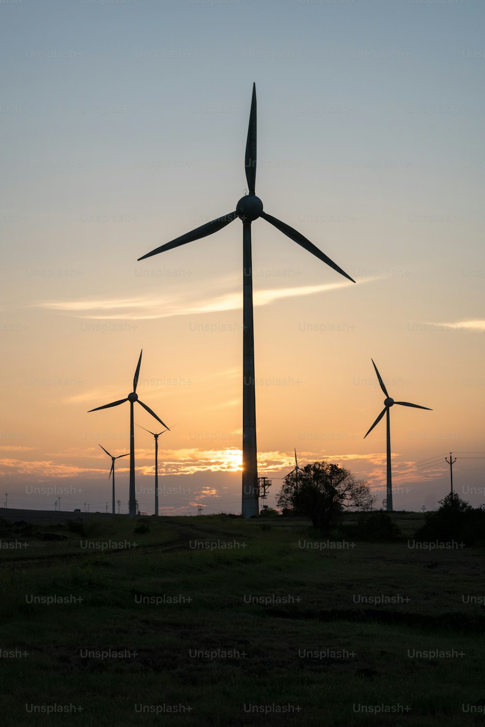 Un gruppo di mulini a vento in un campo al tramonto