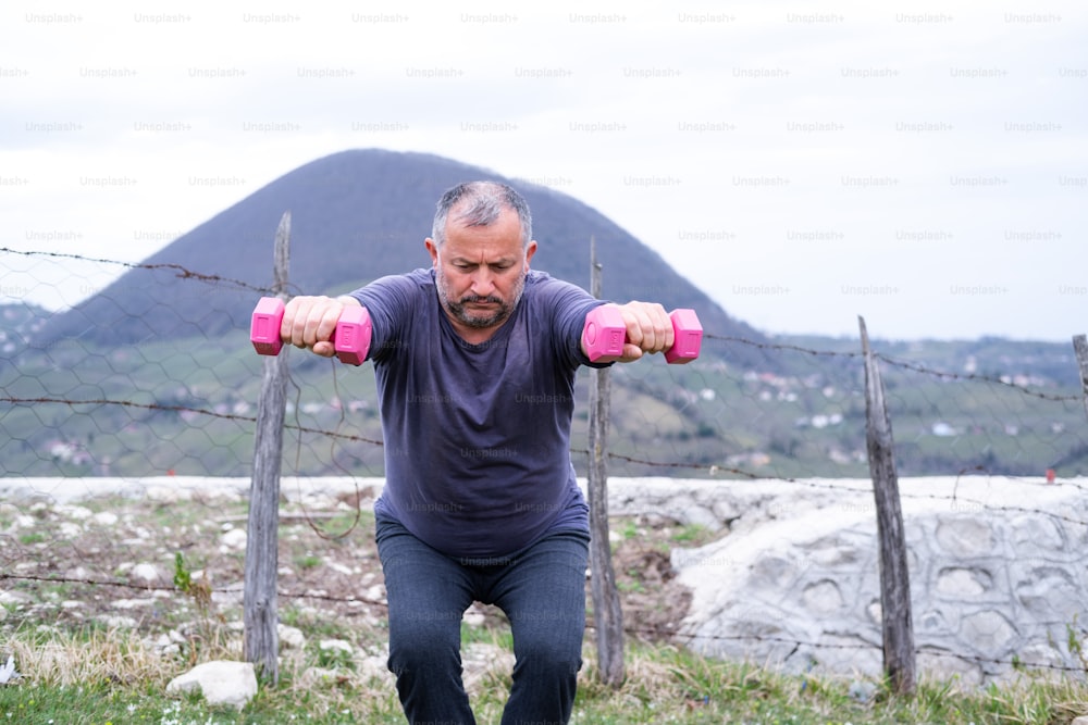 a man is doing exercises with pink dumbs