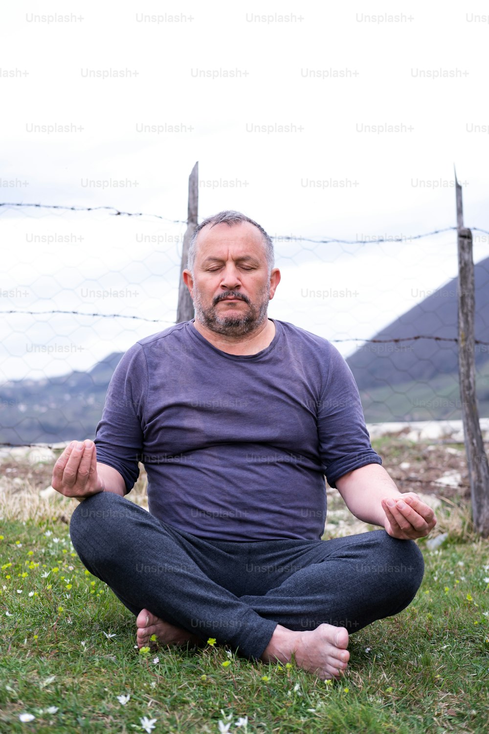 Ein Mann, der in einer Yoga-Position im Gras sitzt