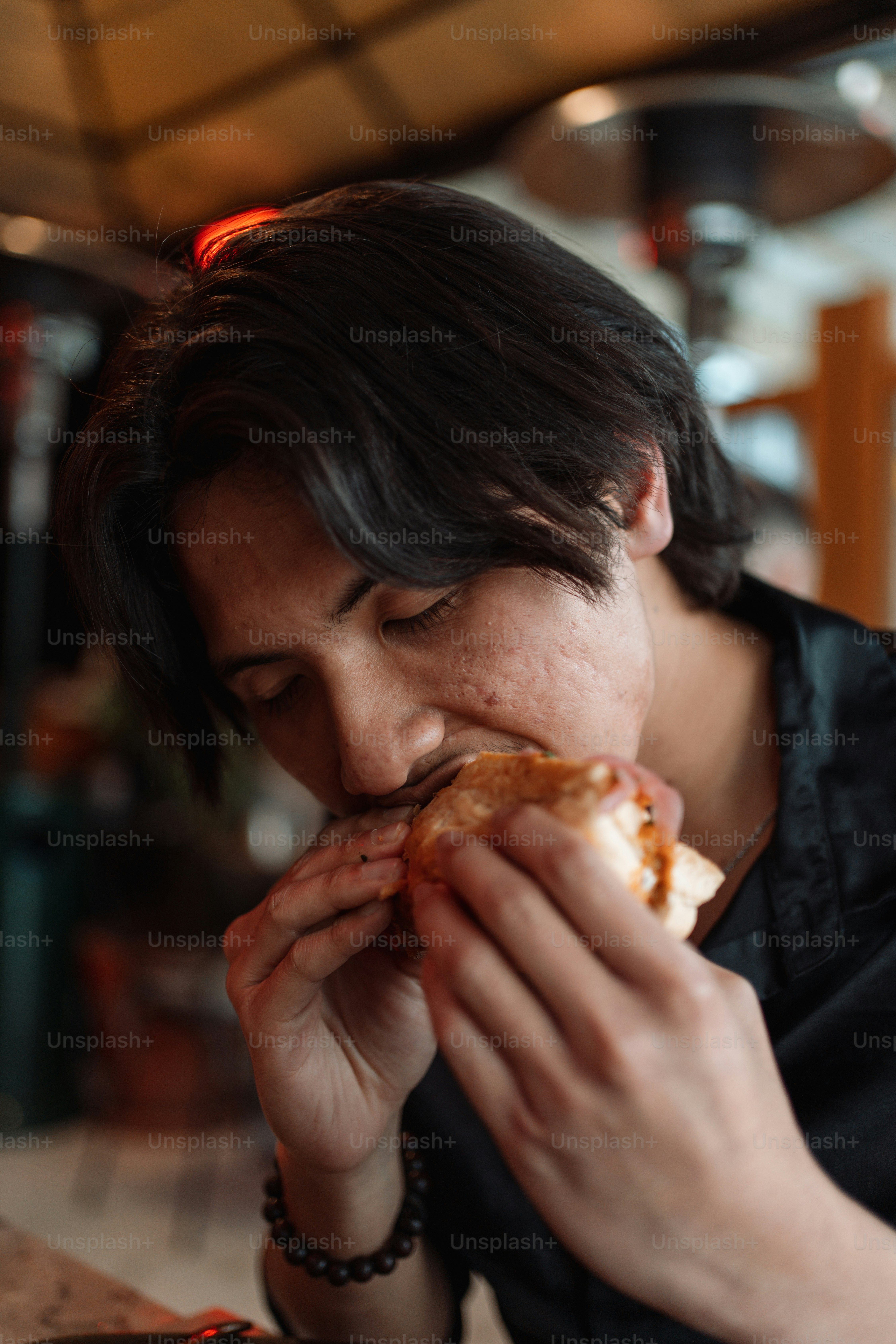 a woman sitting at a table eating a hot dog
