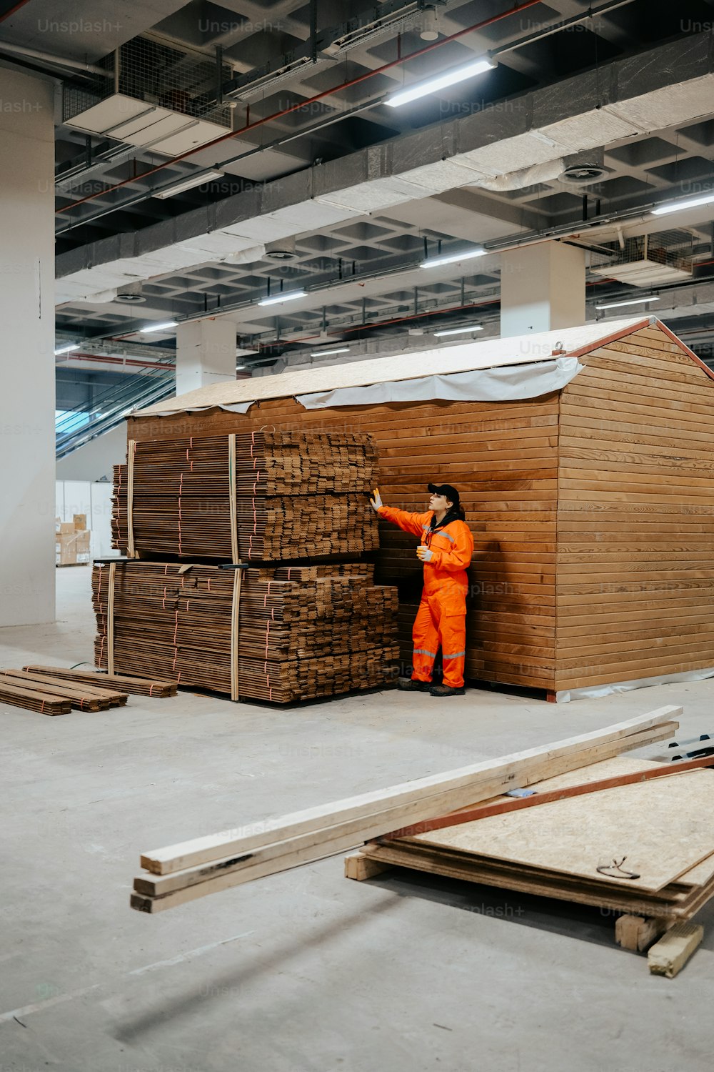 a person in an orange jumpsuit standing next to stacks of wood