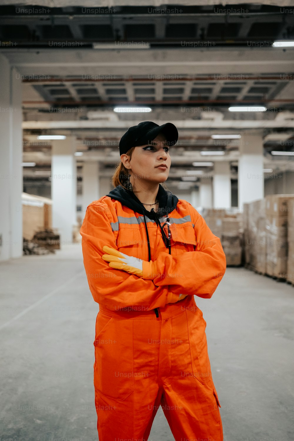 a woman in an orange jumpsuit standing in a warehouse