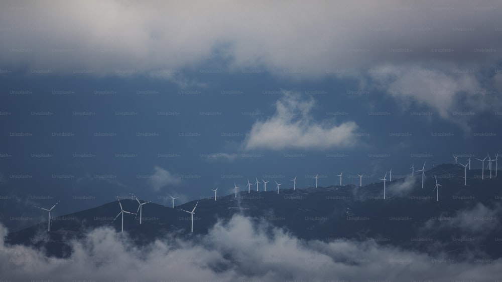 a group of windmills on a hill surrounded by clouds