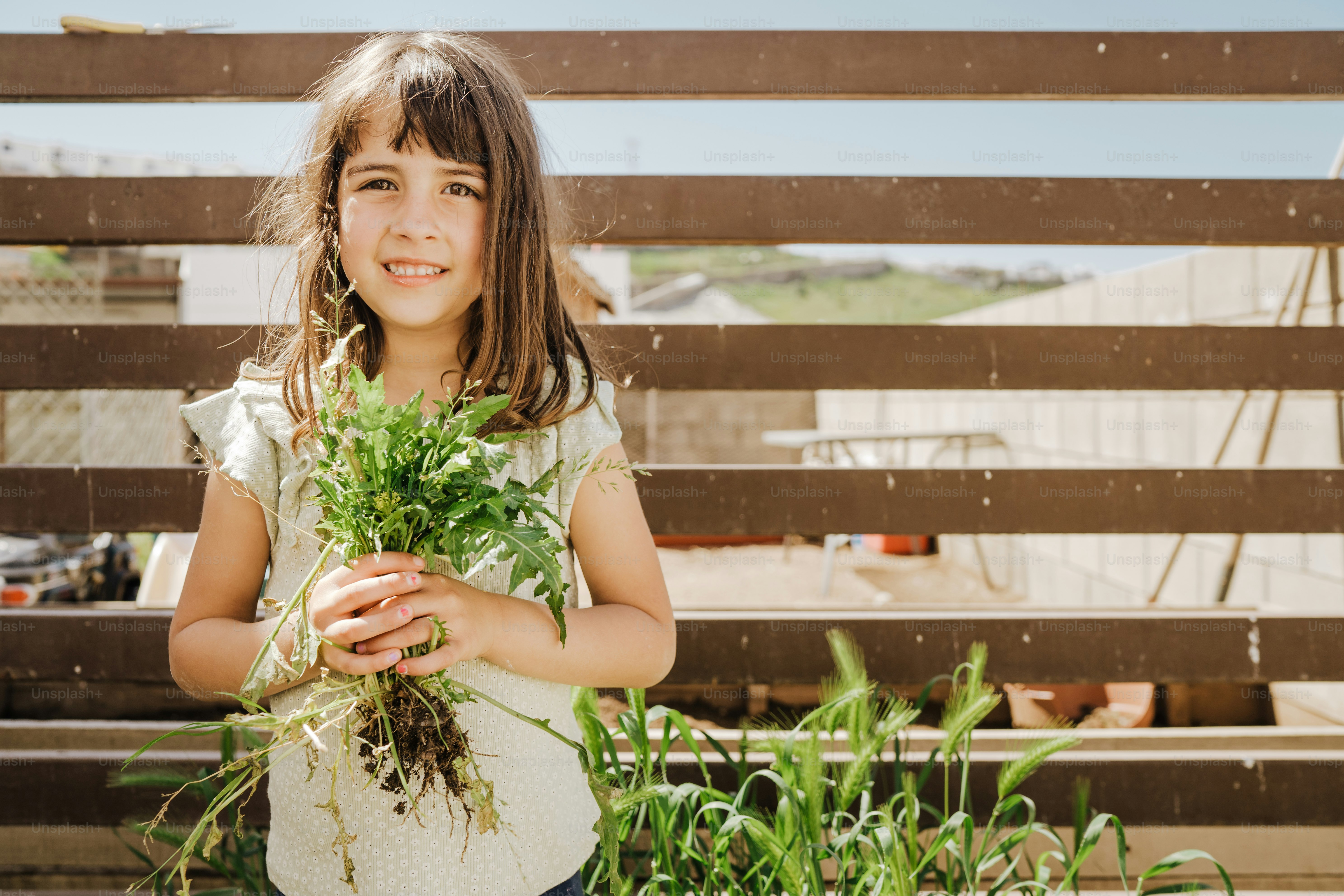 a young girl holding a bunch of green plants