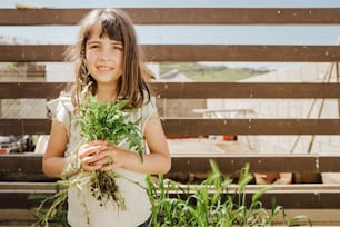 a young girl holding a bunch of green plants