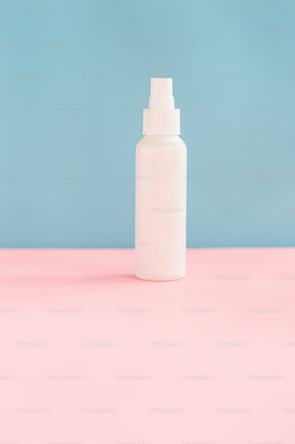 a white spray bottle sitting on top of a pink table