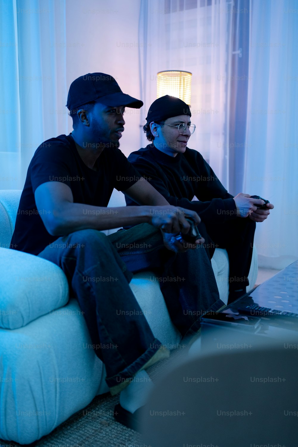 two men sitting on a couch playing a video game