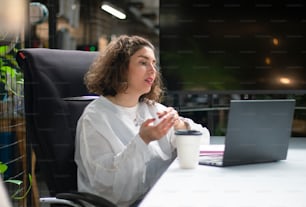 a woman sitting at a desk in front of a laptop