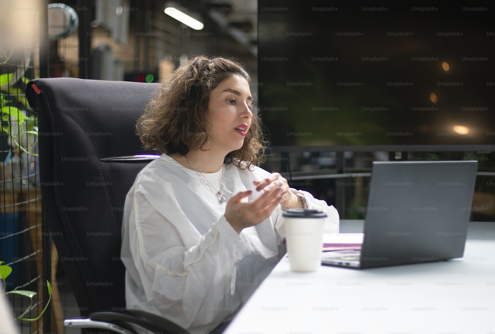 a woman sitting at a desk in front of a laptop