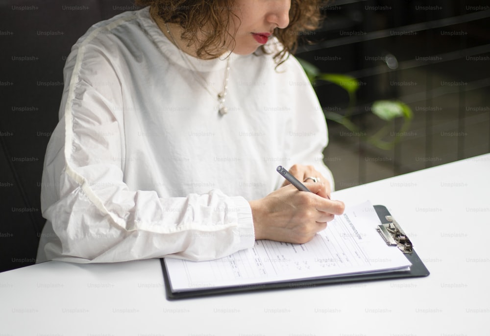 Una mujer sentada en una mesa escribiendo en un pedazo de papel
