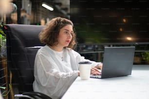 ノートパソコンを持って机に座っている女性