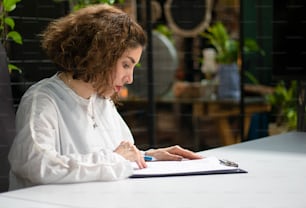 a woman sitting at a table writing on a notebook