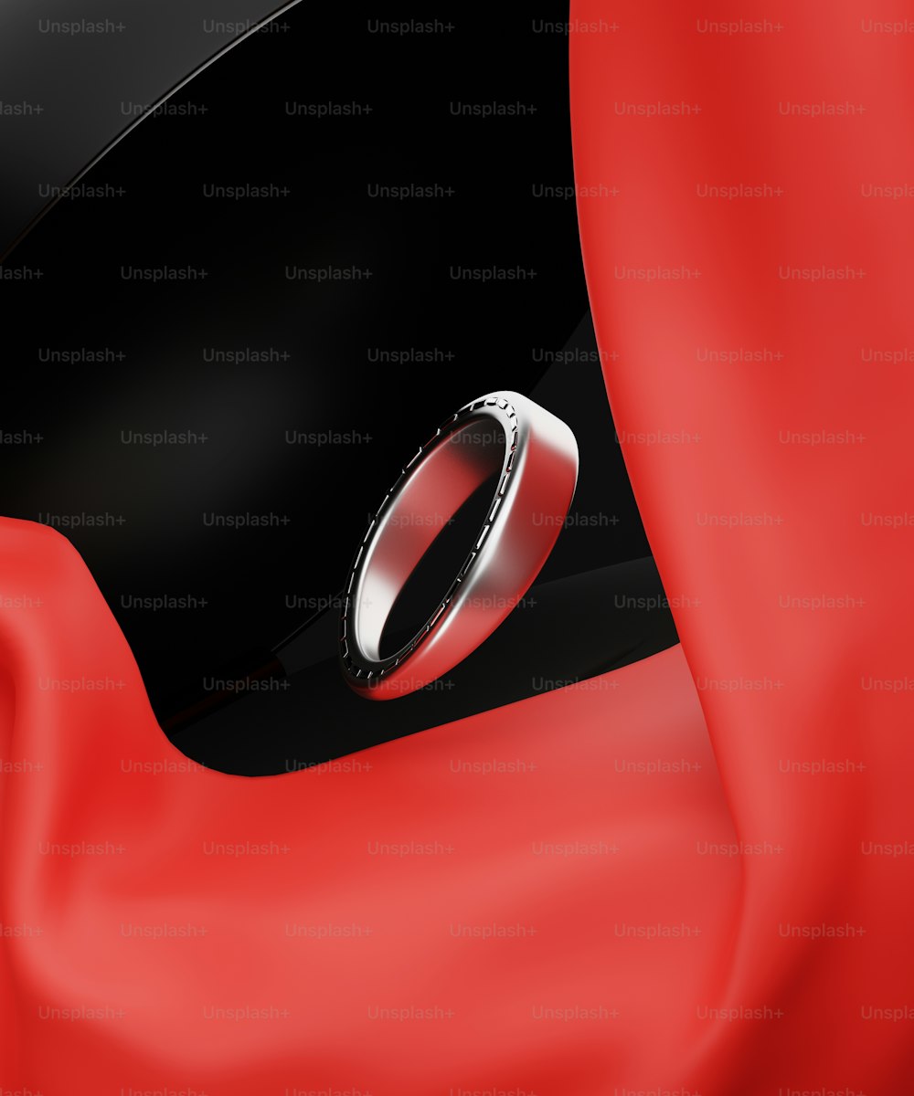 um anel preto e vermelho sentado em cima de um pano vermelho