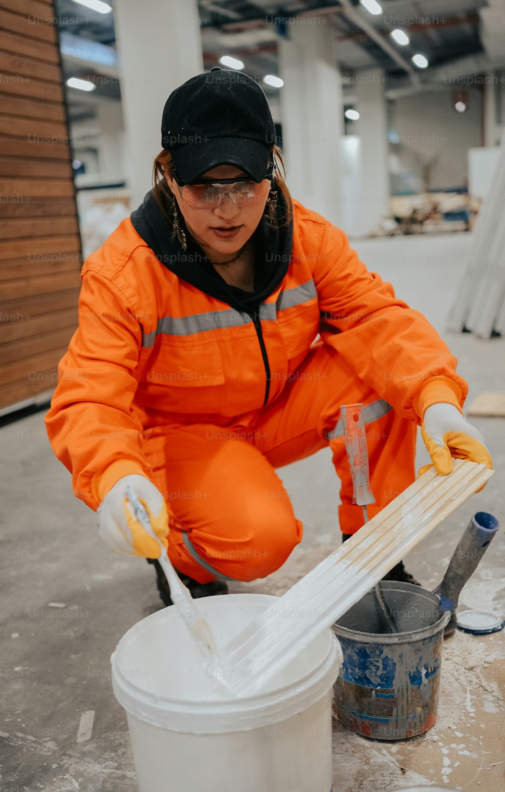 Eine Frau in einem orangefarbenen Overall putzt einen Eimer