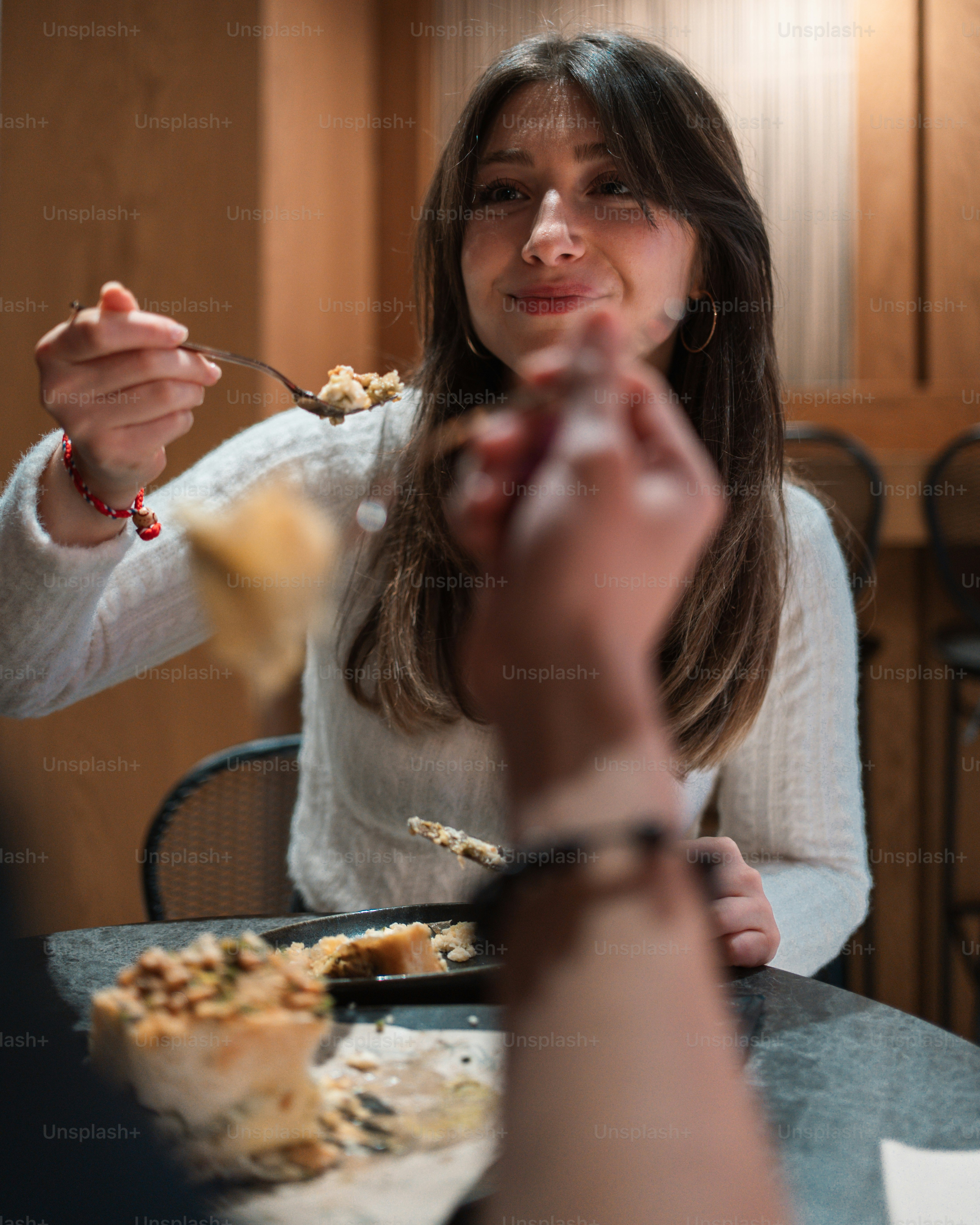 Una mujer comiendo alimentos de un plato con un tenedor