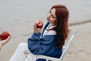a woman sitting in a chair eating an apple
