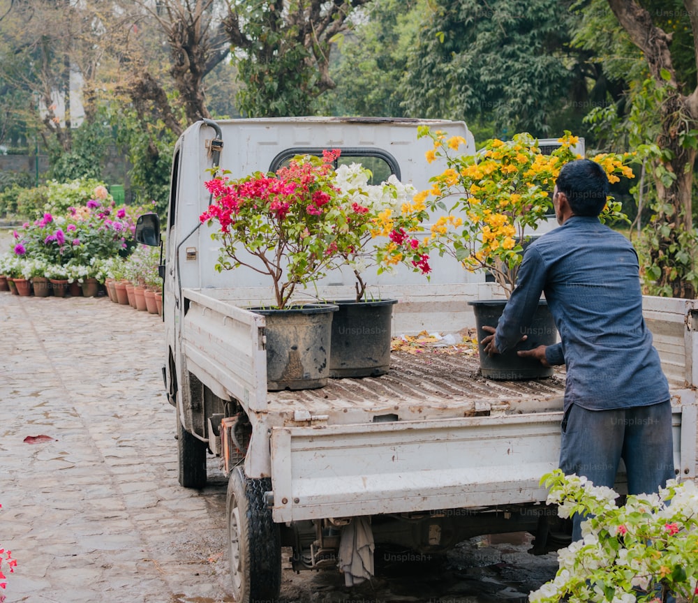 a man standing next to a truck filled with flowers