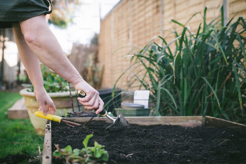a person digging in a garden with a garden tool